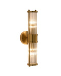 Brimsley II wall sconce featuring a vertical brass mount with ripple-textured clear glass panels and two glowing light sources, creating a warm, refined ambiance.