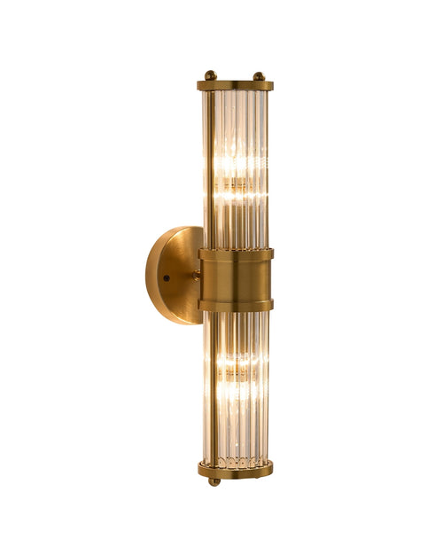 Brimsley II wall sconce featuring a vertical brass mount with ripple-textured clear glass panels and two glowing light sources, creating a warm, refined ambiance.