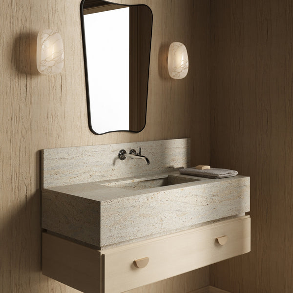 Butterfly-shaped wall mirror with a slim dark frame mounted above a stone vanity sink, flanked by two wall sconces in a neutral-toned bathroom.