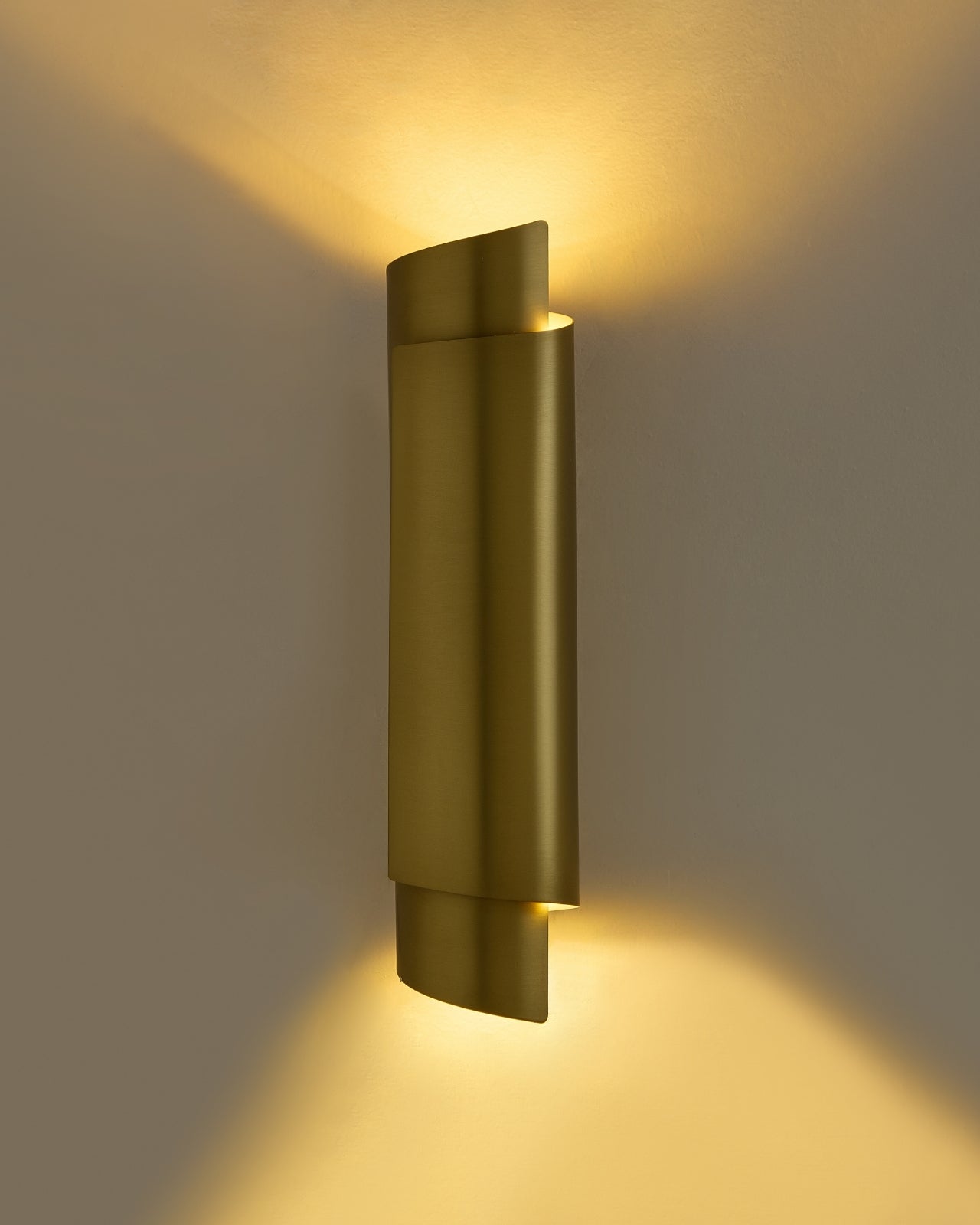 Introvert Wall Sconce in brushed brass, mounted on a wall and emitting soft up-and-down ambient light.