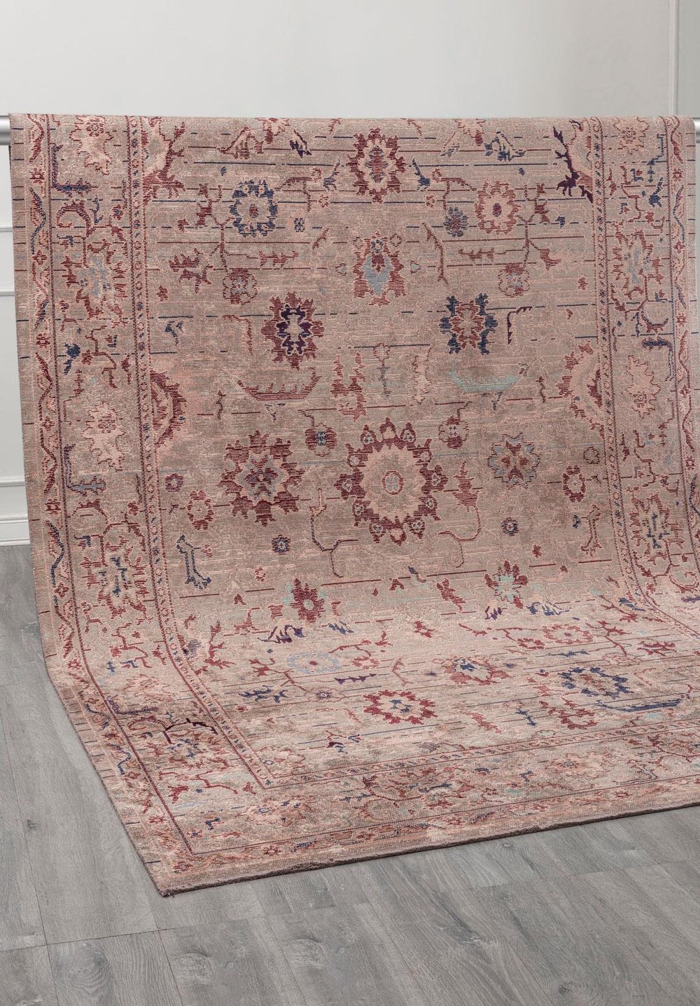 Traditional area rug with a central medallion and bordered design shown in neutral and muted accent colors.