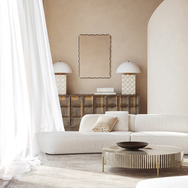 Rectangular wall mirror with a black frame and softly wavy edges, mounted above a sideboard in a neutral living room setting.
