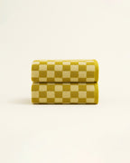 Two mustard and white checkered towels neatly rolled and stacked, showcasing the geometric pattern and soft terry texture on a neutral background.