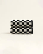 Two black and white checkered towels neatly rolled and stacked, showcasing the geometric pattern and soft terry texture on a neutral background.