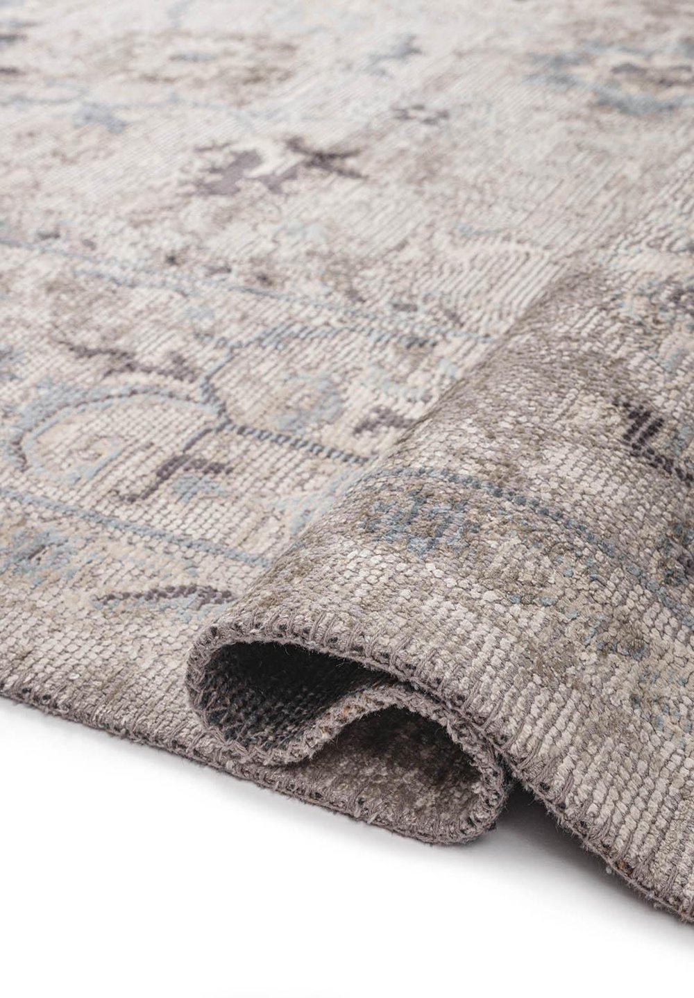 Close-up of a flat-woven rug with a muted gray and blue pattern and folded edge.