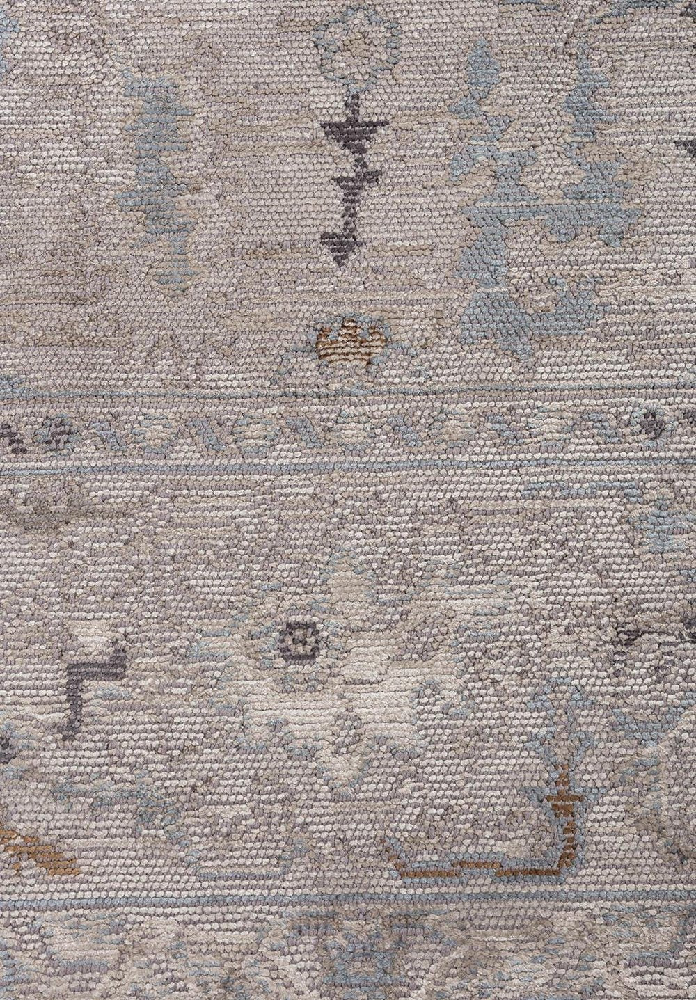 Close-up of a flat-woven rug with a muted gray and blue geometric pattern.
