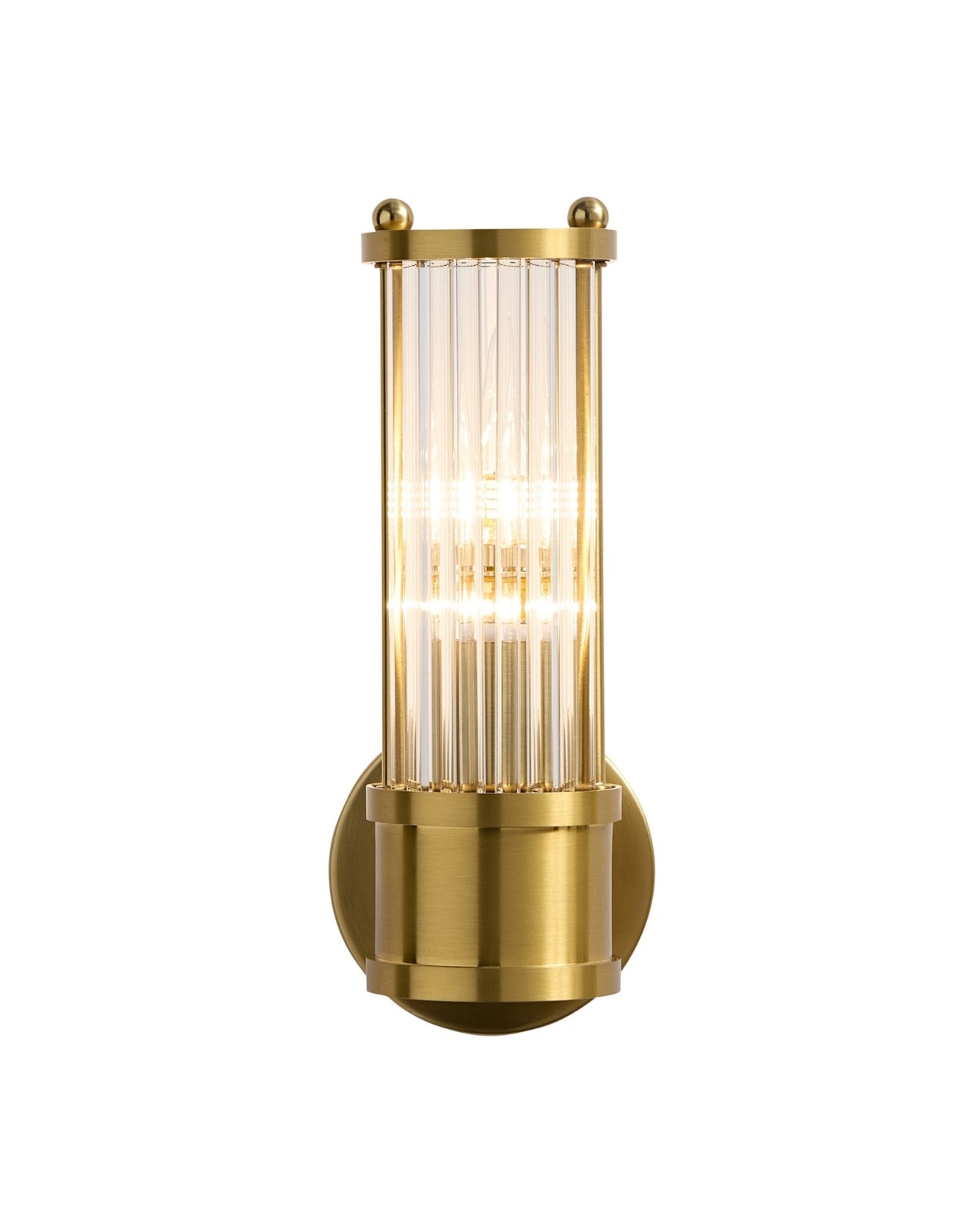 Wall-mounted brass sconce with a cylindrical clear glass shade featuring vertical ribbed texture, shown illuminated against a white background.