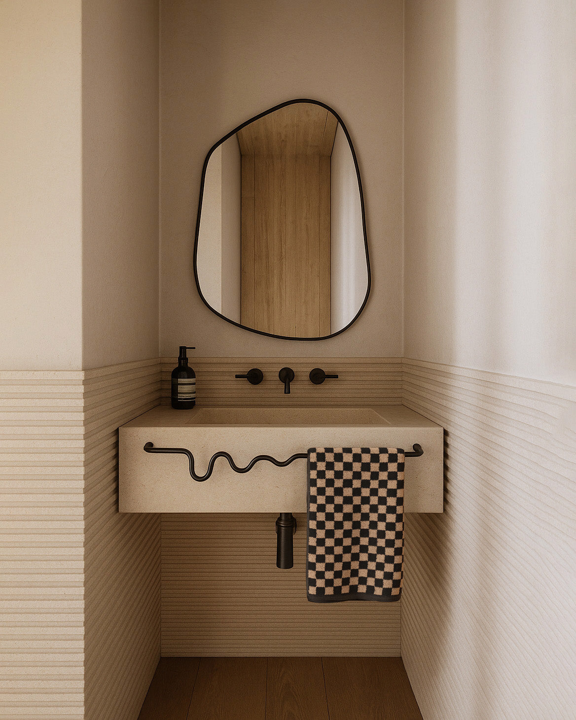 Black-framed organic mirror above a beige wall-mounted sink with a wavy towel bar and checkered hand towel.