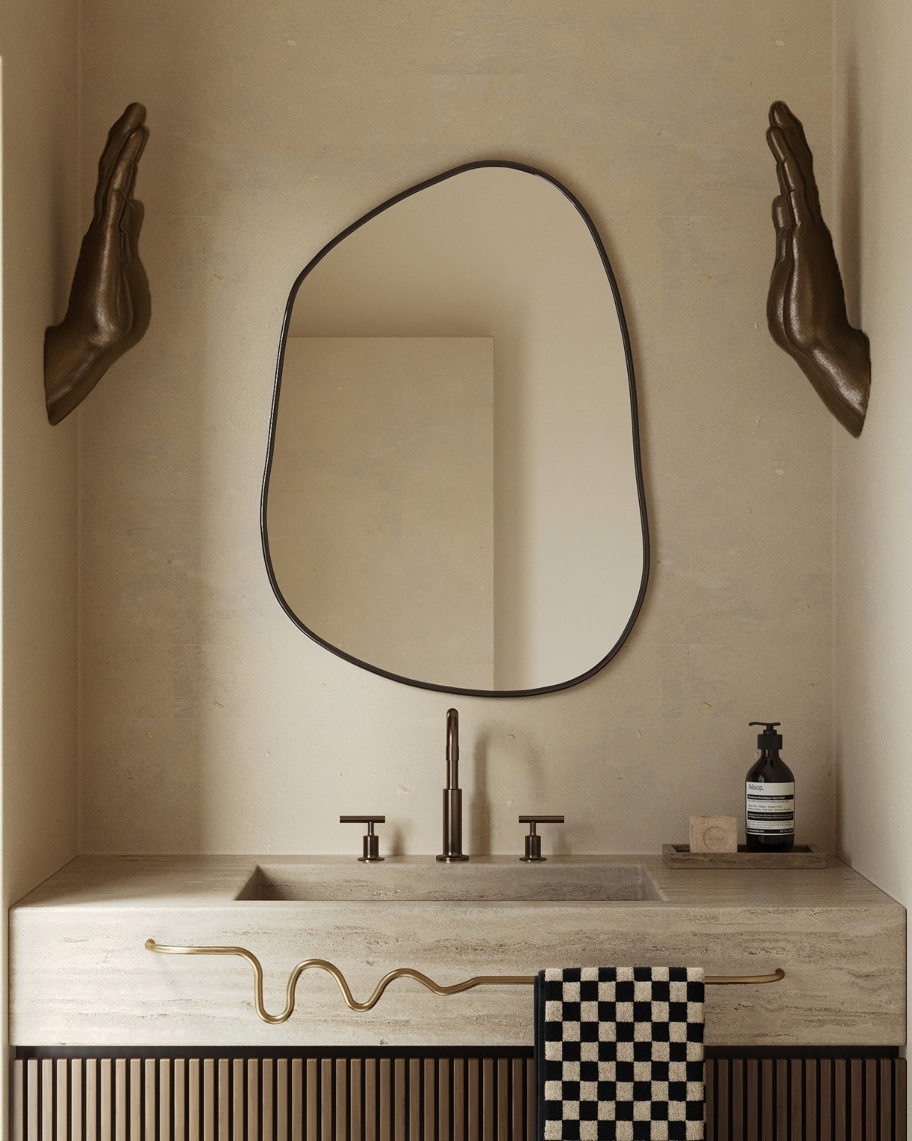 Asymmetrical wall mirror mounted above a stone bathroom vanity with bronze fixtures.