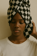 Model wearing a black and white checkered towel wrapped around the head, highlighting the soft terry texture and geometric pattern against a neutral background.