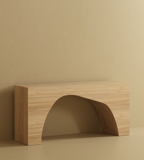 A rectangular console table with a flat top and a large arched opening at the base, made of wood veneer and placed against a plain wall and floor.