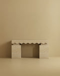 Travertine console table with a rectangular top featuring a scalloped carved edge and two solid block legs.