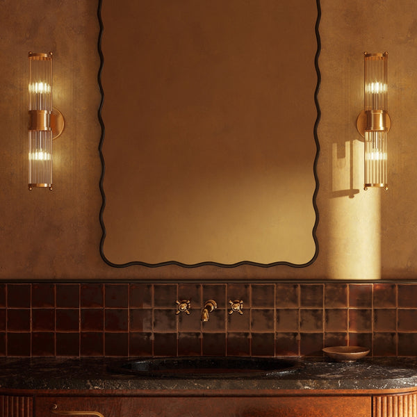 Rectangular wall mirror with a black frame and softly wavy edges, mounted above a bathroom vanity between two wall sconces.