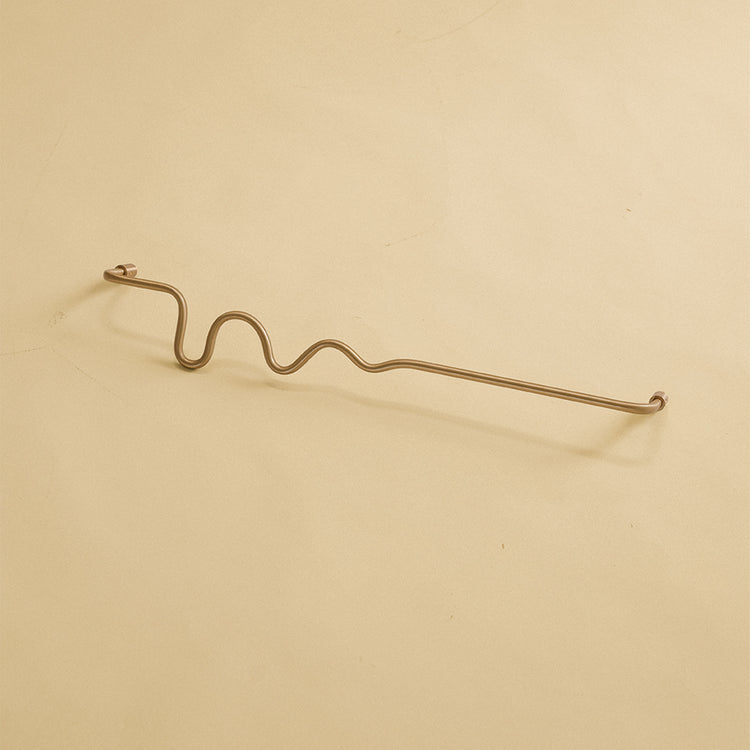 Wavy brass towel bar displayed on a neutral studio background.