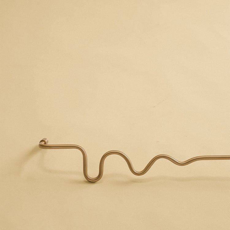 Wavy brass towel bar shown as a studio product image against a plain light background.