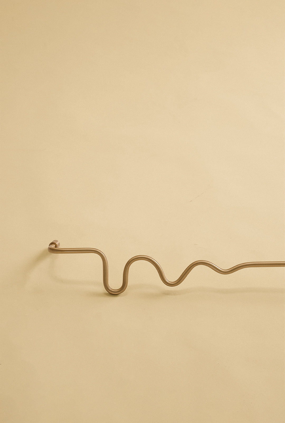 Wavy brass towel bar shown as a studio product image against a plain light background.