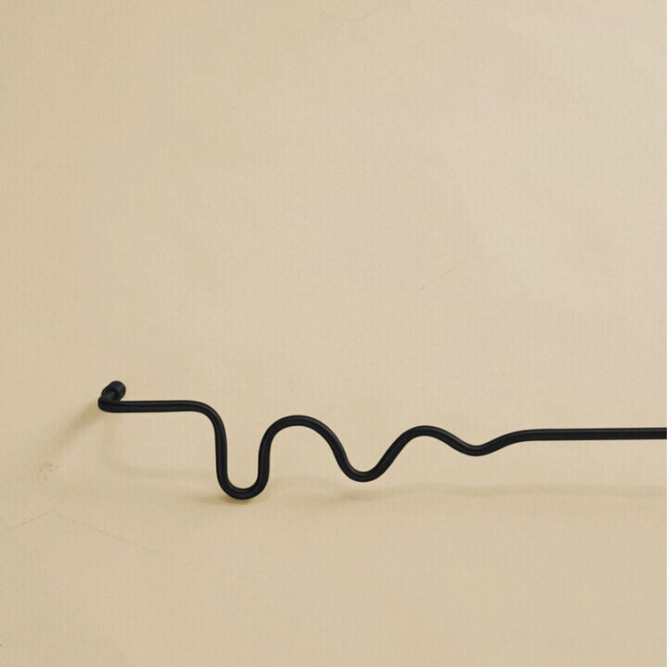 Black wavy brass towel bar shown as a studio product image against a plain light background.