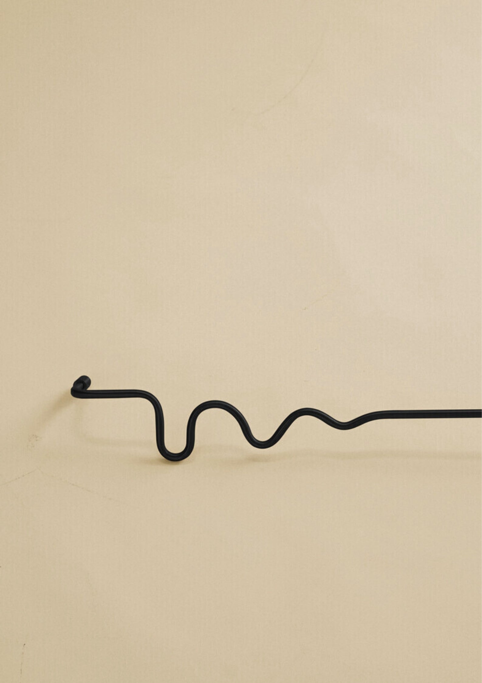 Black wavy brass towel bar shown as a studio product image against a plain light background.