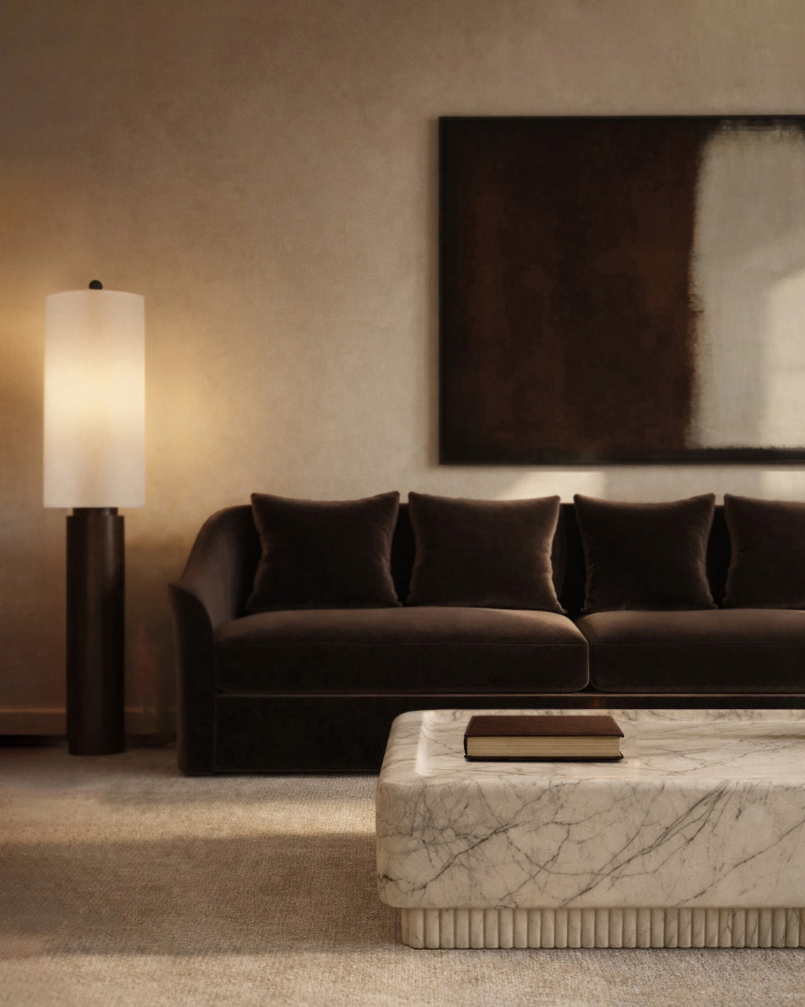 Dark brown sofa with pillows, marble coffee table with a book, and a tall floor lamp beneath a large abstract wall art in a warm-toned living room.