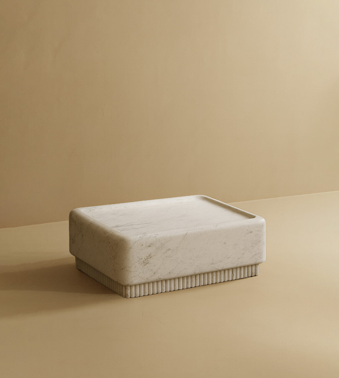 Square coffee table made from white marble with subtle natural veining, featuring a solid block top and a low, ribbed base.