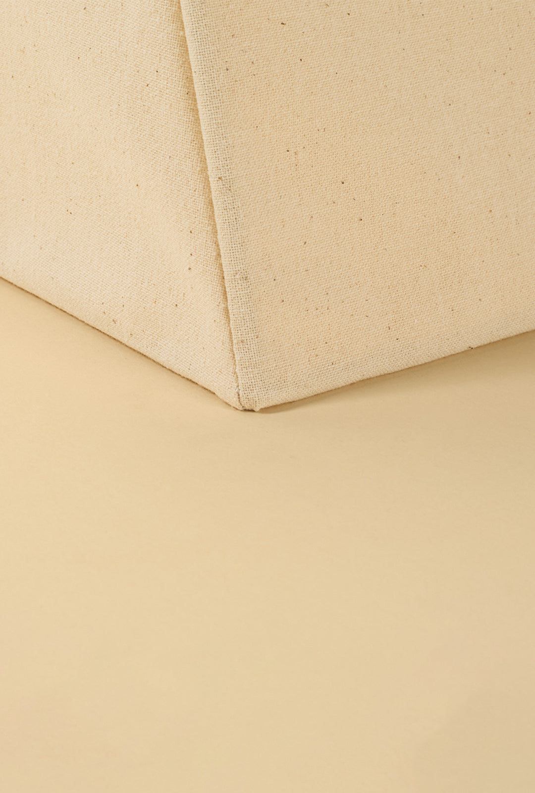 Close-up of a linen table lamp highlighting the natural fabric texture and stitched corner detail.