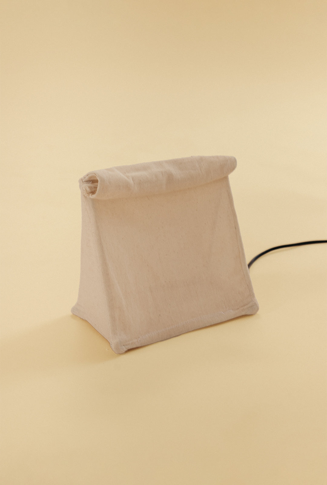 Lunch Bag Lamp made of natural linen fabric, shown unlit with its signature folded top design.