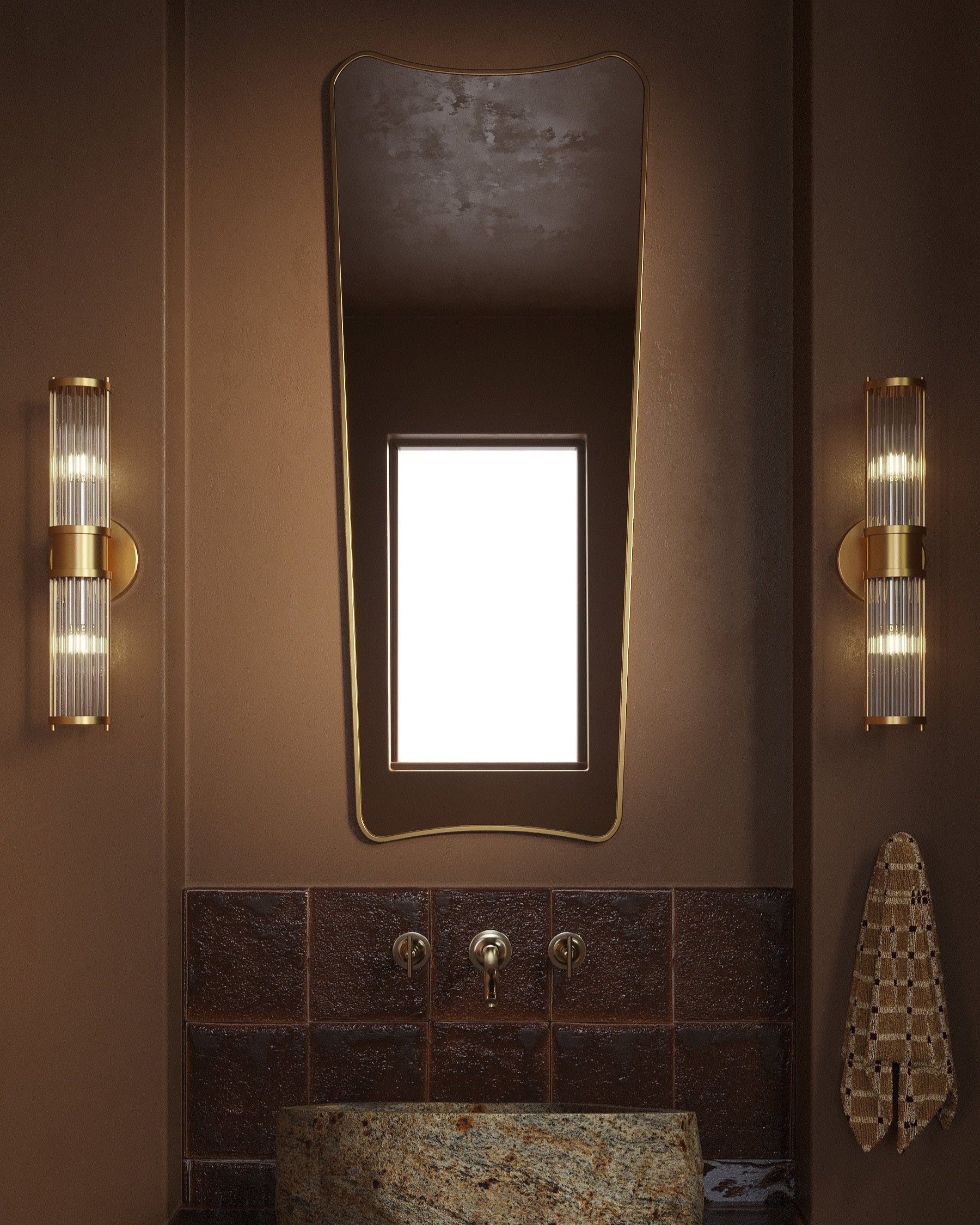 Full-length mirror with a softly curved, asymmetrical silhouette mounted above a bathroom sink, flanked by two wall lights in a warm-toned interior.