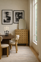 Wooden storage cabinet with a sculptural front of evenly spaced rounded wooden spheres, placed in a dining area beside a window, styled with a mirror on top and surrounded by a wooden dining table and upholstered chairs.