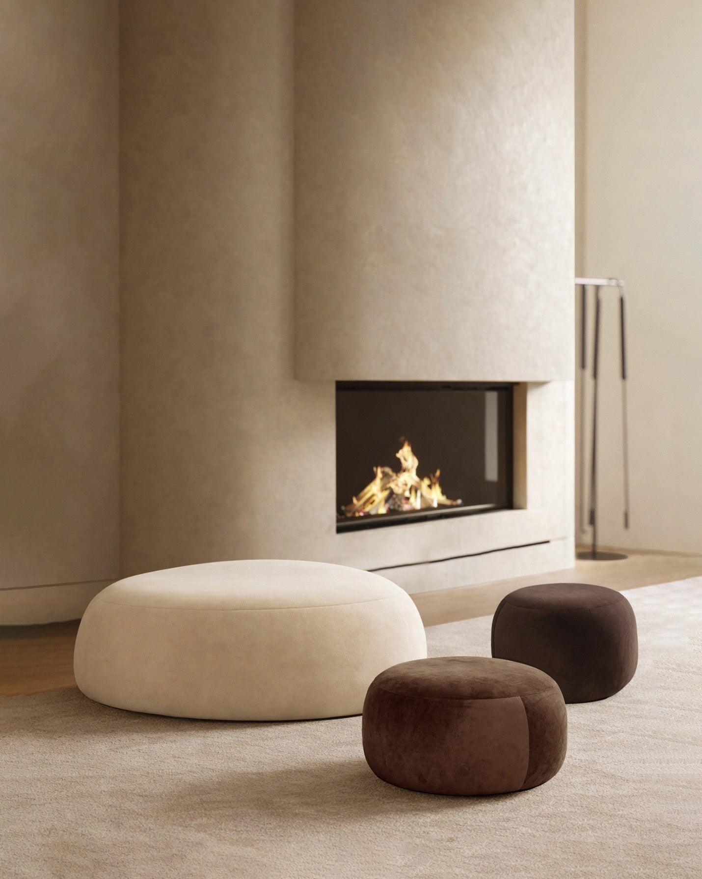 Three round upholstered ottomans in different sizes arranged on a rug before a built-in fireplace.