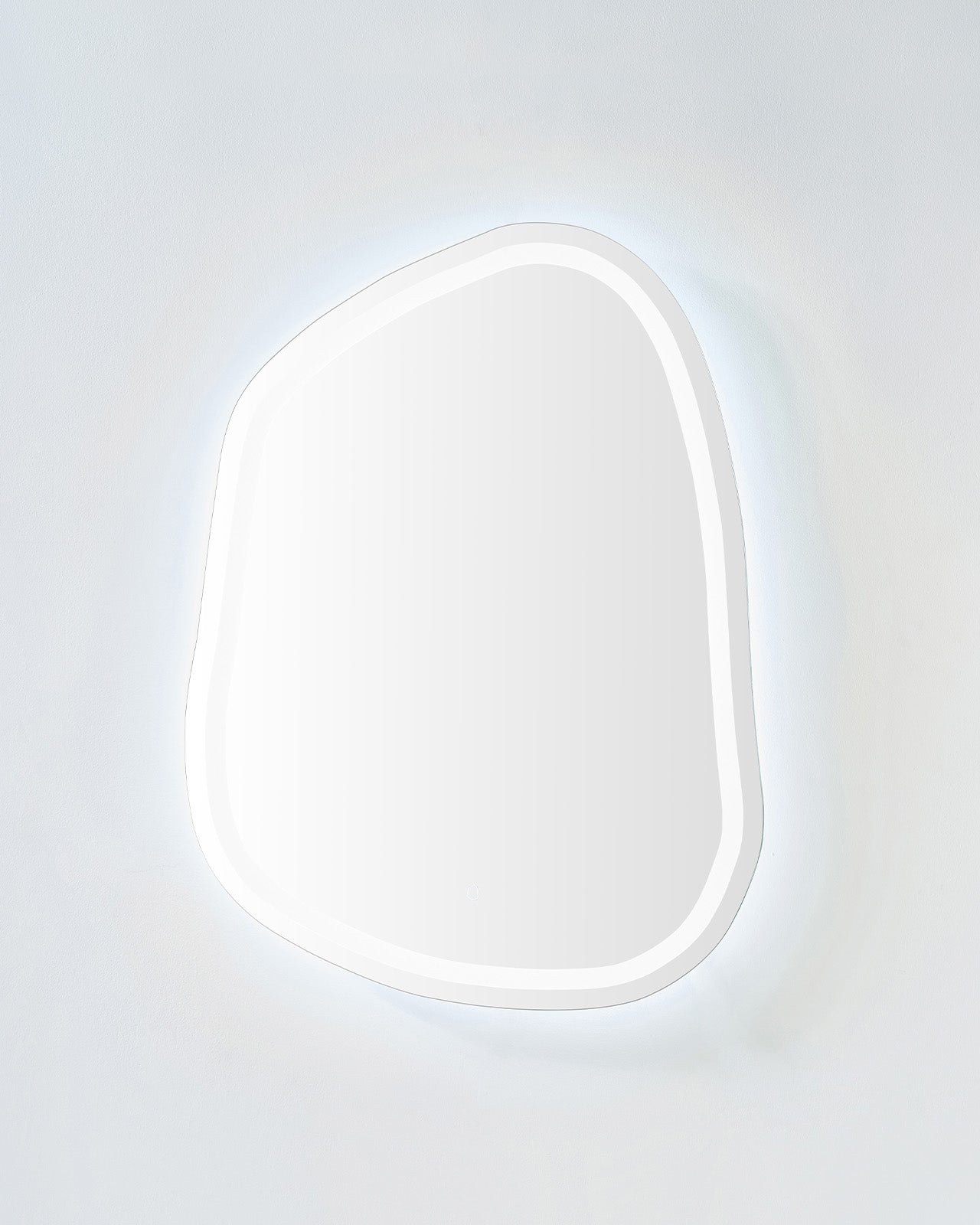 Organic-shaped LED mirror with soft cool backlit glow on a light-colored wall.