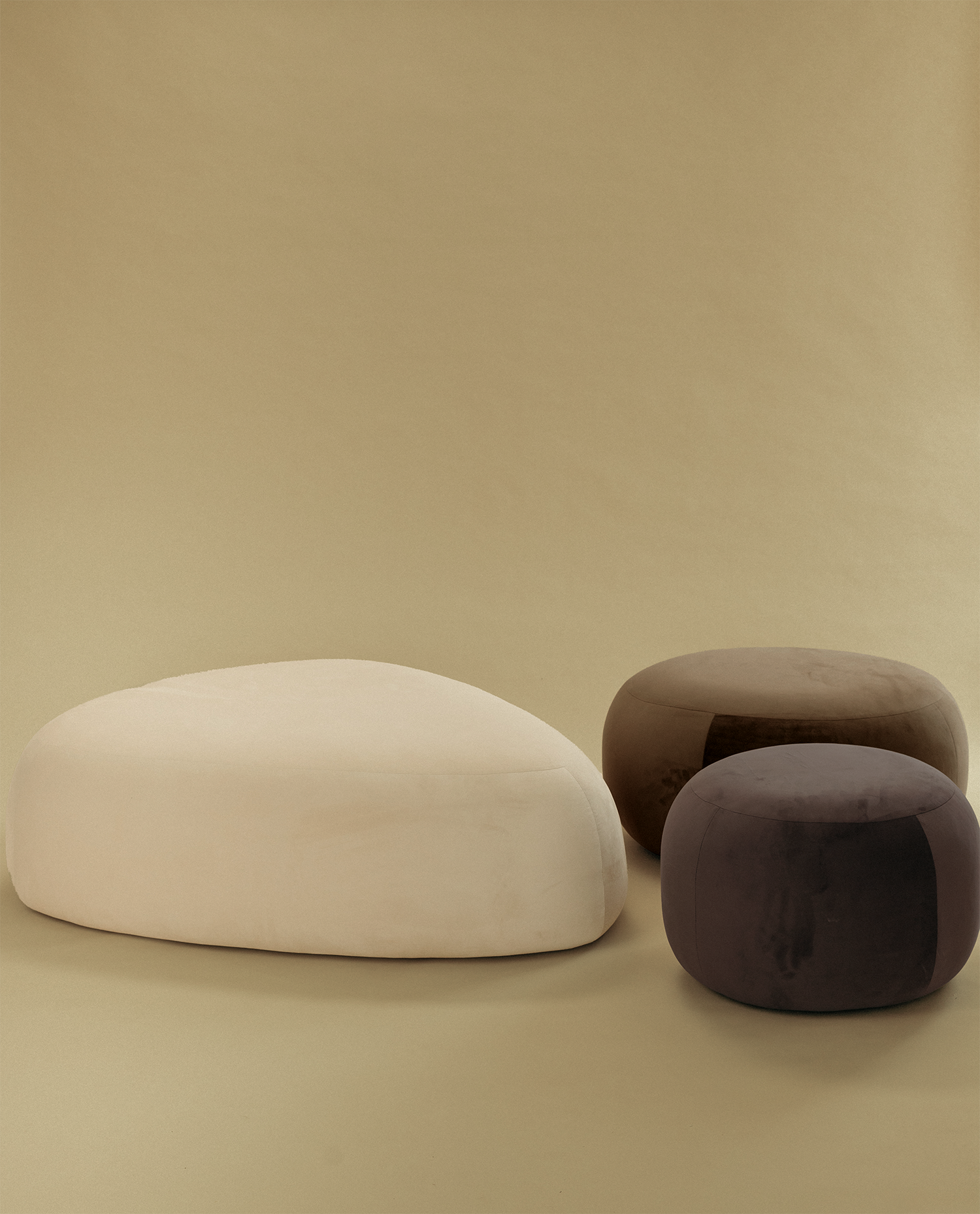 Pebble ottoman set with one large light-colored ottoman and two smaller dark-toned ottomans on a neutral background.