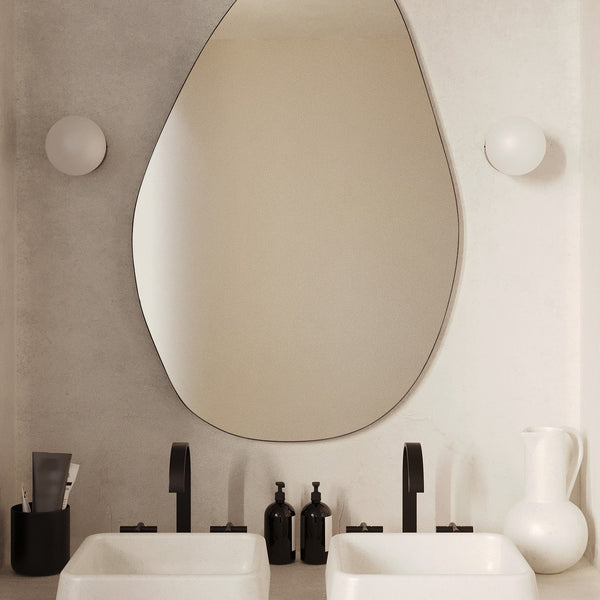 Pebble-shaped frameless wall mirror mounted above a double bathroom vanity.