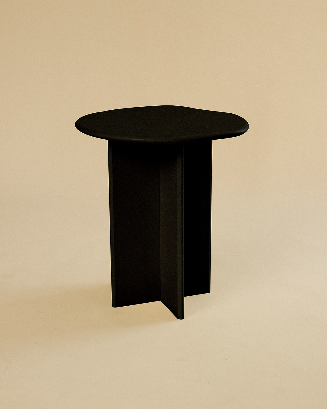 A minimalist black side table with a round tabletop and three vertical legs, photographed against a neutral studio background.