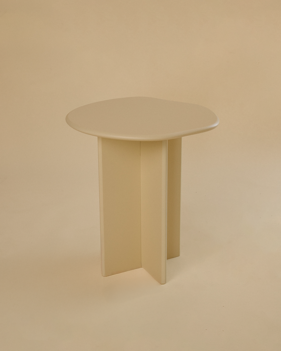 A minimalist light yellow side table with a round tabletop and three vertical legs, photographed from a slightly elevated angle against a neutral studio background.