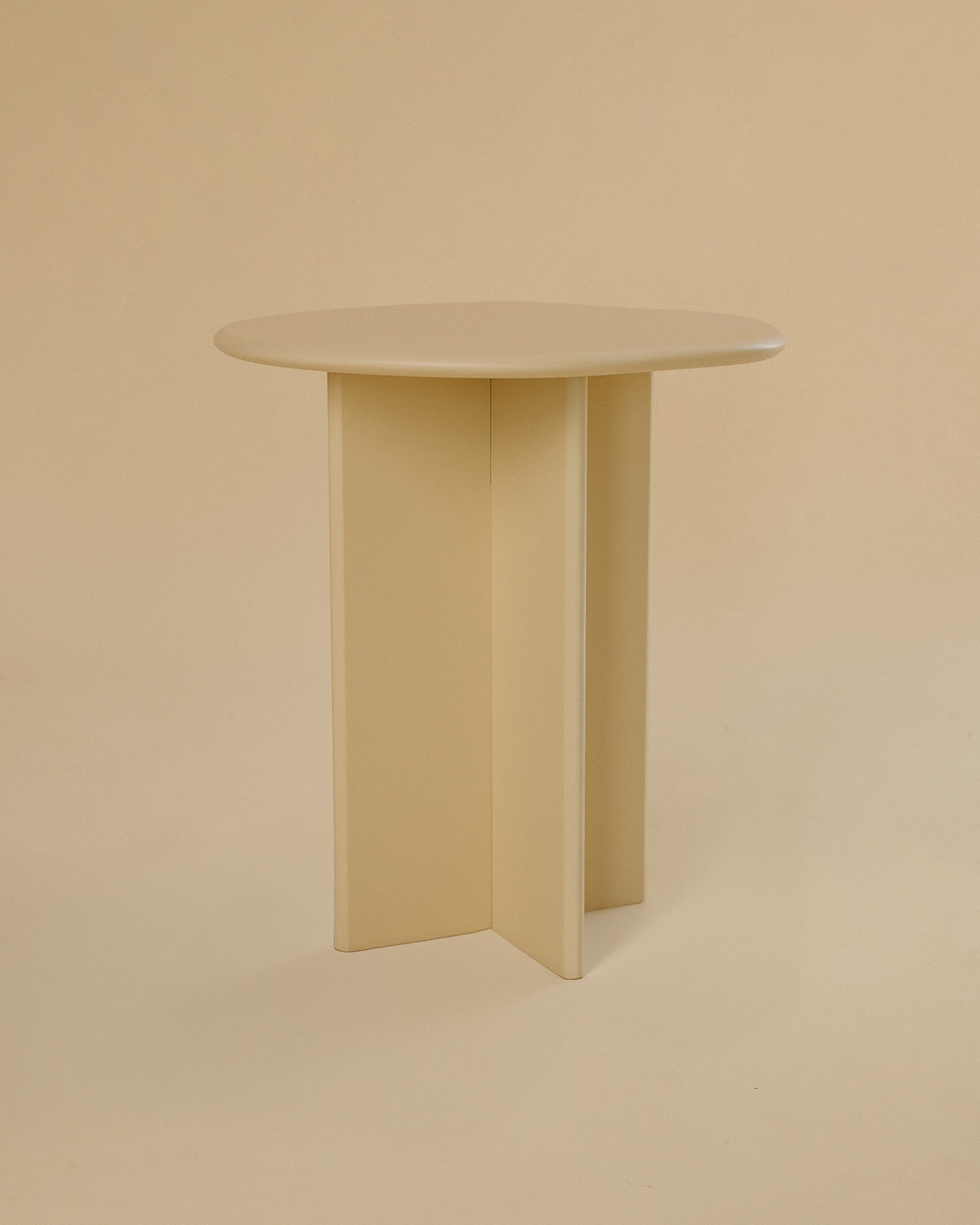 A minimalist light yellow side table with a round tabletop and three vertical legs, photographed against a neutral studio background.