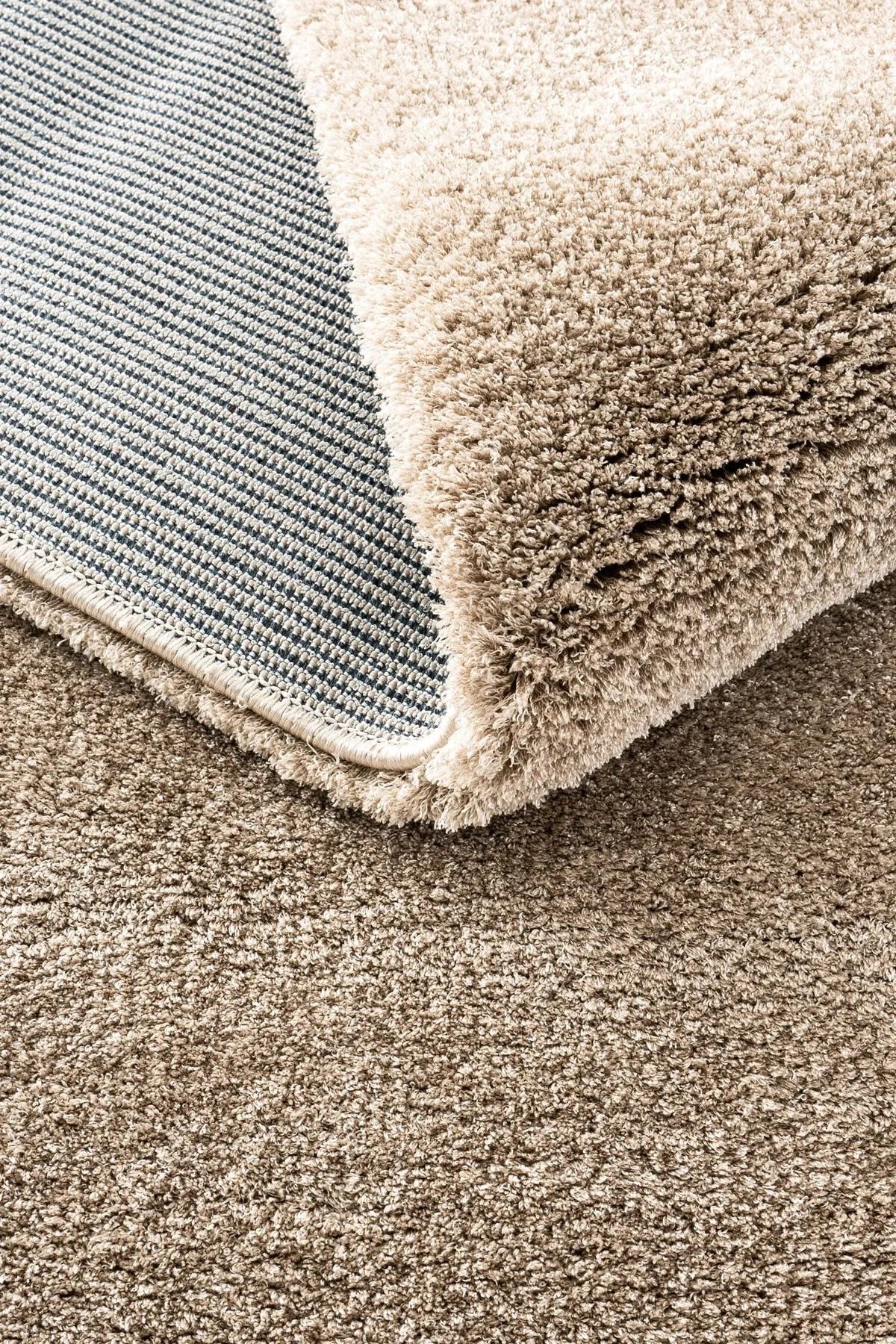 Close-up of a brown plush rug showing thick pile and woven backing.