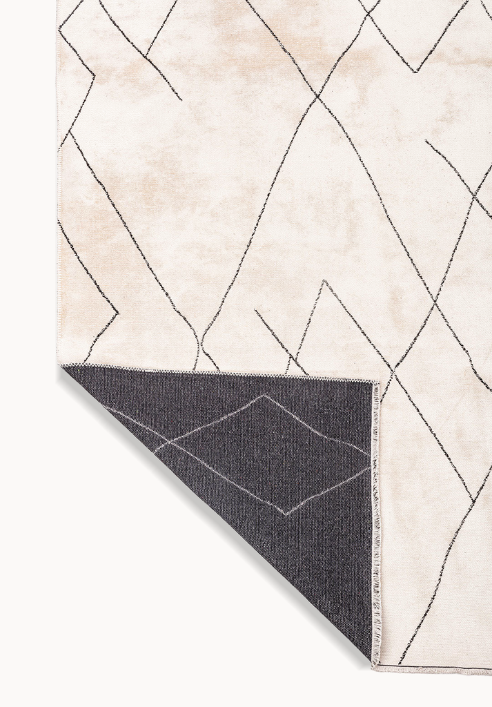 Beige rug corner with abstract line pattern.