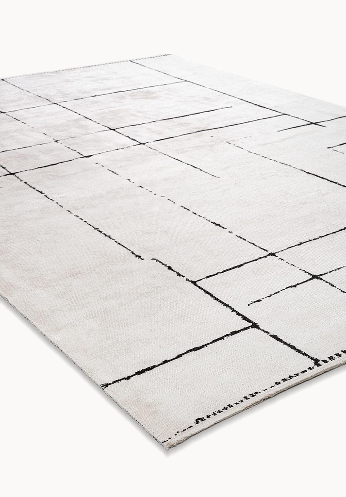 Angled view of a beige flat-woven rug with black abstract grid lines.