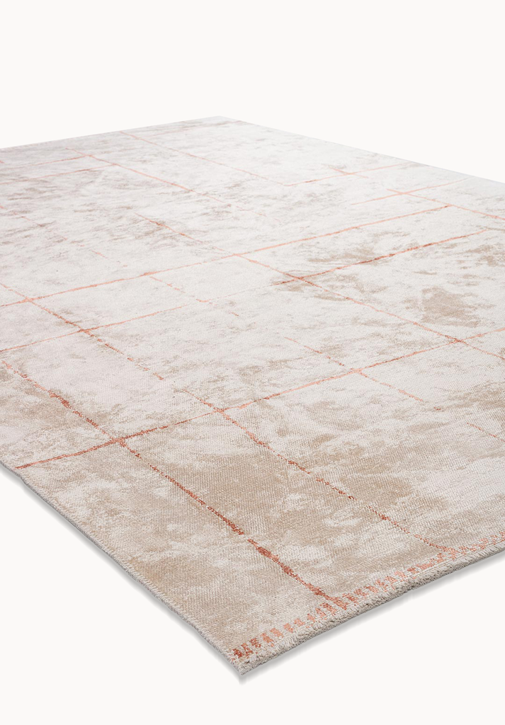 Angled view of a beige area rug with subtle blush grid pattern.