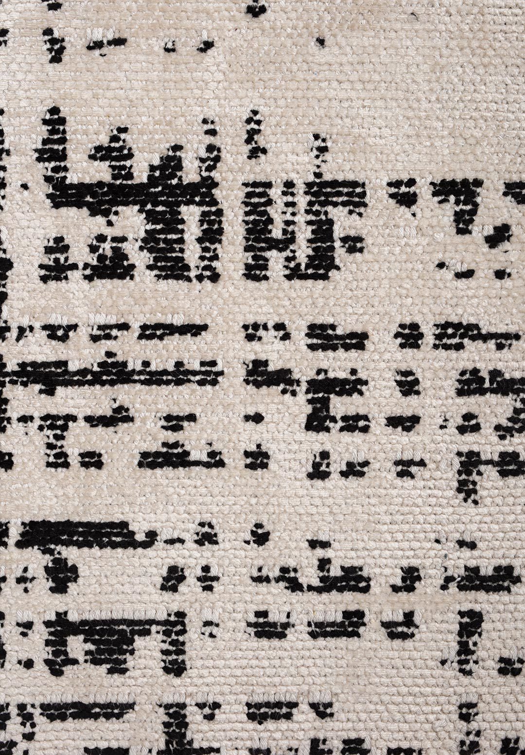 Close-up of beige flat-woven rug with black distressed pattern.