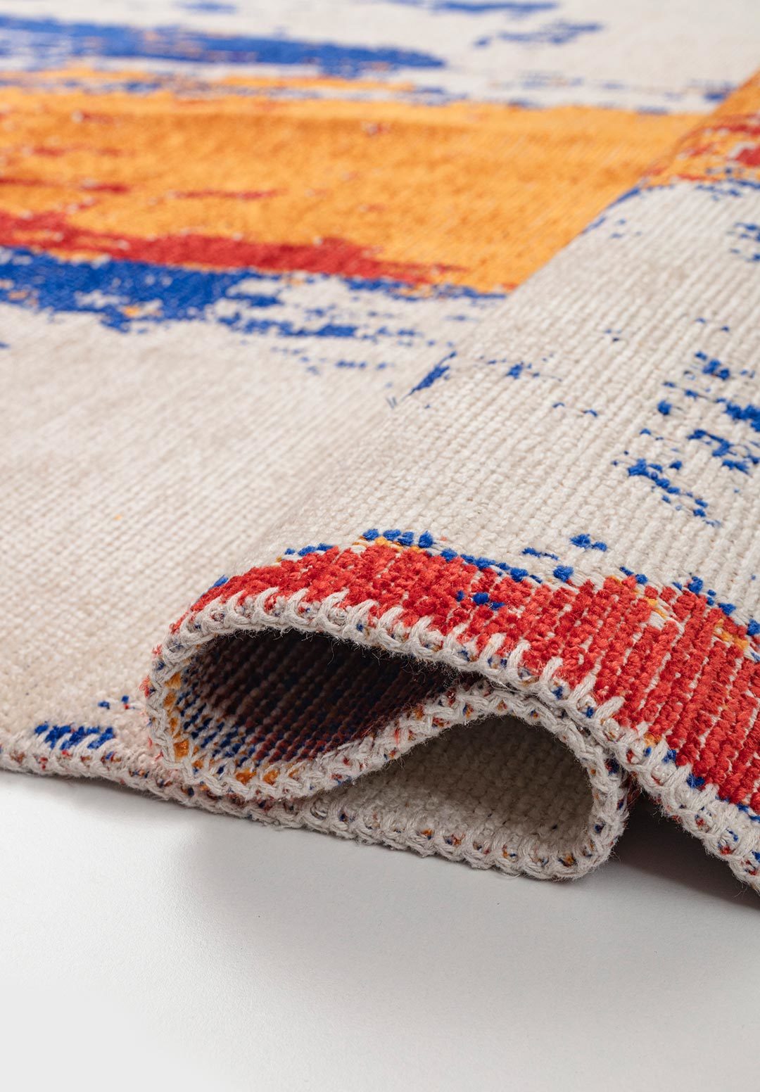 Close-up of abstract multicolor flat-woven rug with folded edge detail.