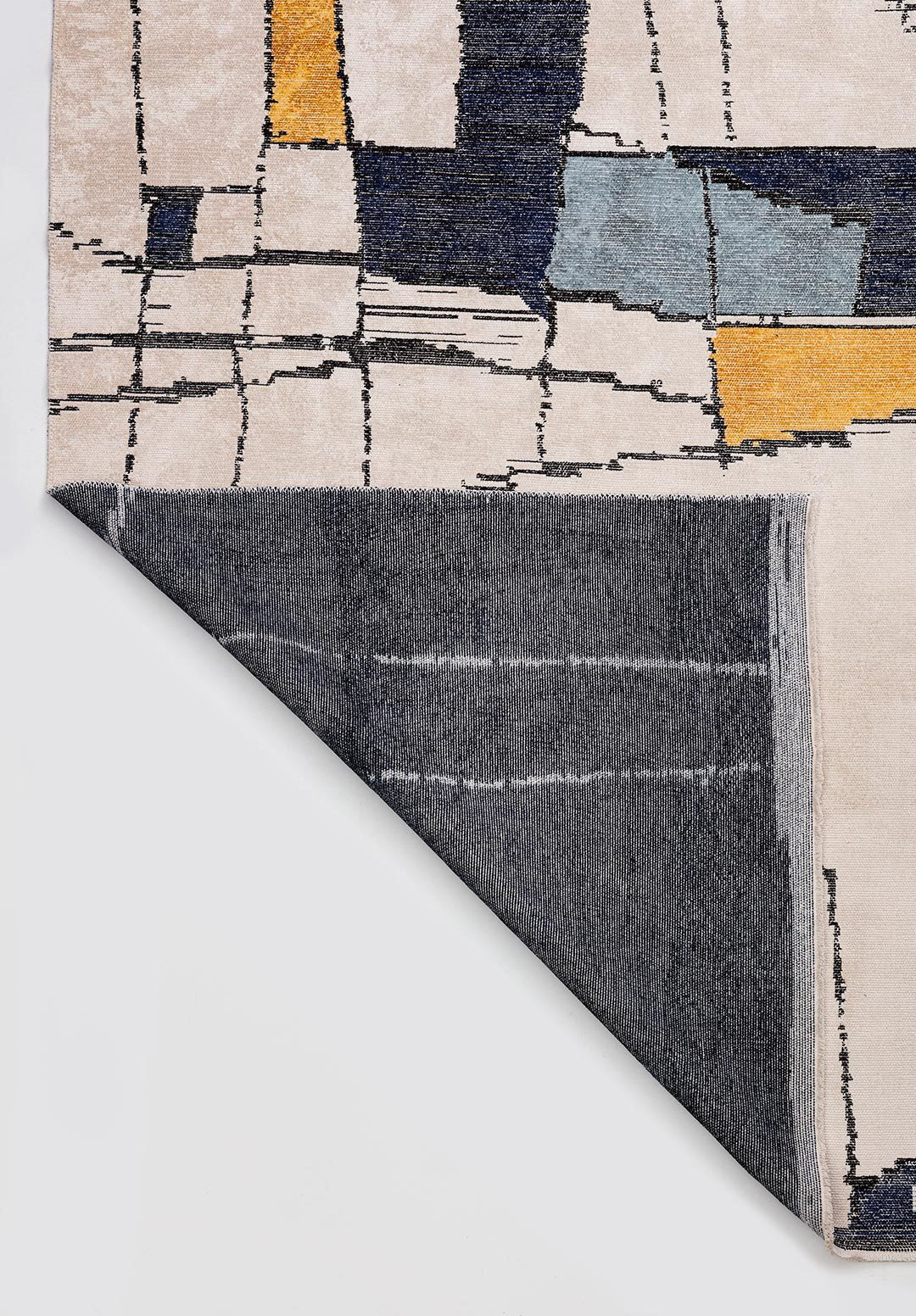 Corner of flat-woven rug with geometric pattern and folded edge.