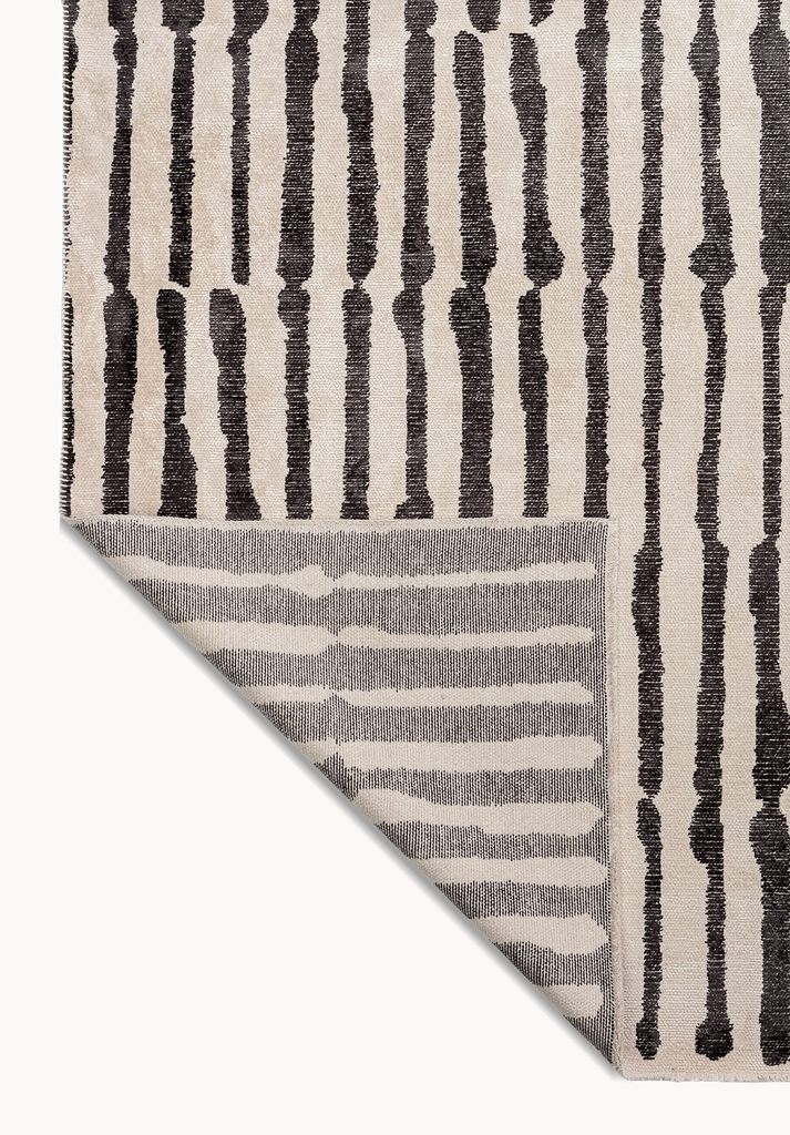Corner of a striped area rug showing the patterned backing and flat-woven construction.