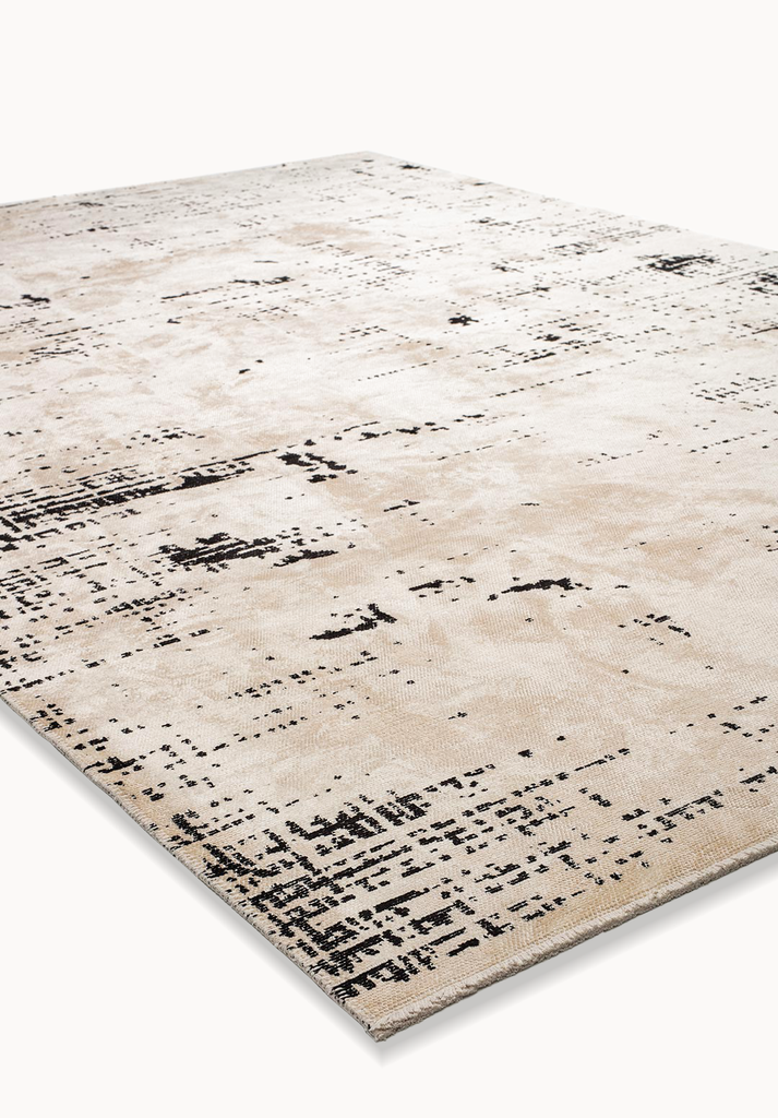 Angled view of a beige flat-woven rug with black abstract distressed details.