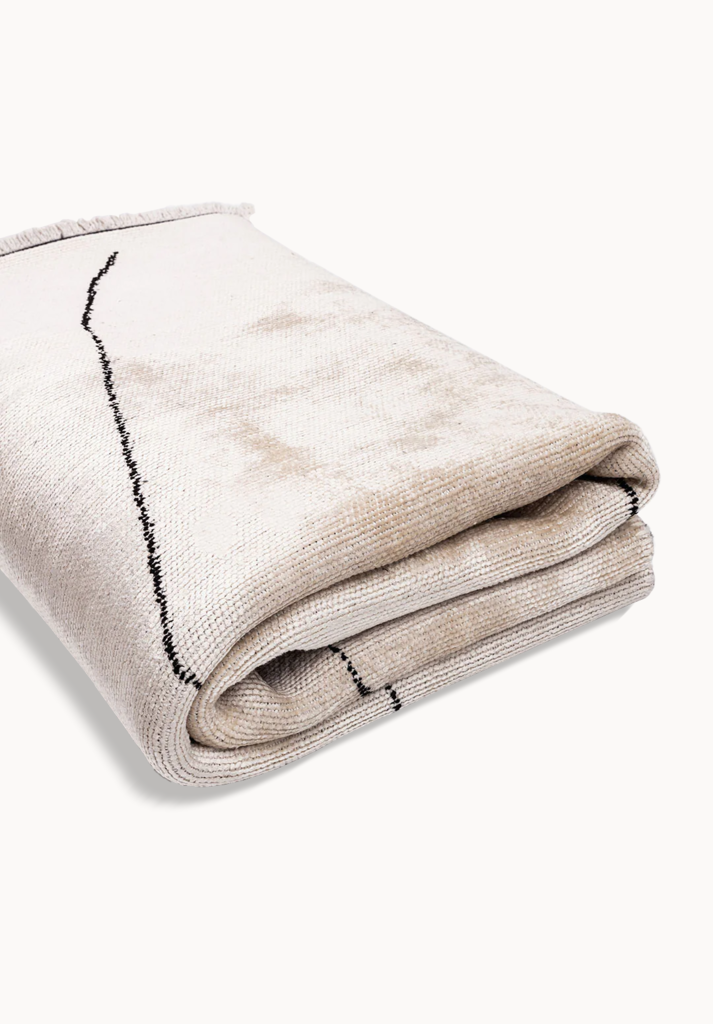 Folded beige rug with thin black line.