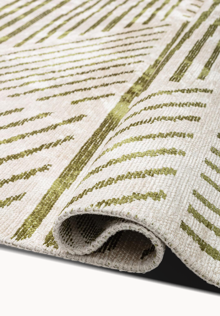 Folded edge of a beige rug with green linear pattern.